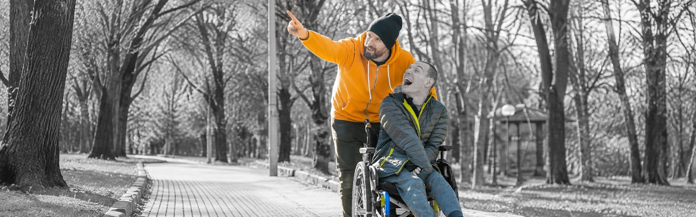 Support worker walking with an NDIS participant in a wheelchair through a park, part of Positive Behaviour Support at Global Rehabilitation Service